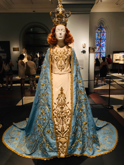 Mannequin dressed as Virgin Mary in satin brocade gown and ornate crown.